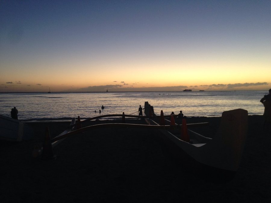 Hawaiian canoe and surfers at the sunset